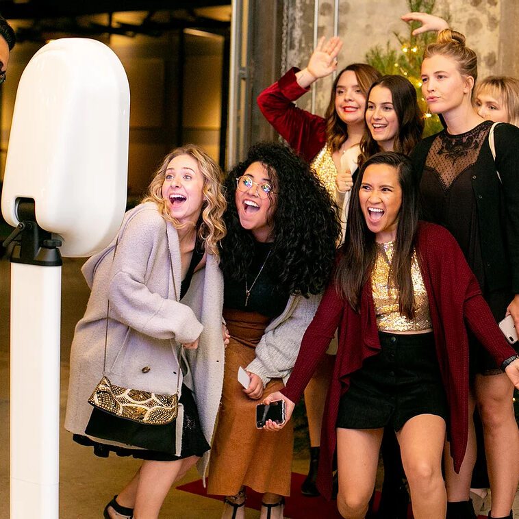 A group of girls standing in front of a photo booth